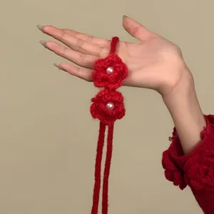 Détail d'un choker fleur rouge en tricot avec des centres de perles blanches.