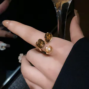 Detailed close-up of a vintage gold-plated open ring featuring a pearl and amber crystals