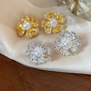 Detailed macro shot of gold and silver flower earrings featuring white pearls and zircons