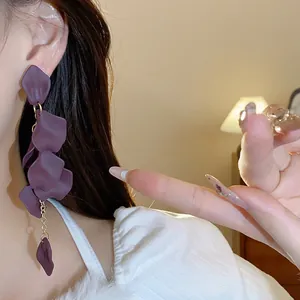 Primo piano di eleganti orecchini a nappa con petali viola indossati per stile.