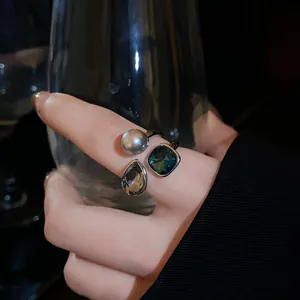 Close-up view of a retro style open ring with pearl and colorful crystals on finger.