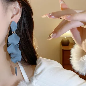 Dettaglio di eleganti orecchini a pendente con nappe a petalo blu su una modella