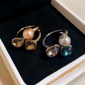 Detail view of gold and silver plated open rings with pearls and square crystals in box