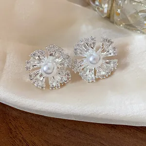 Macro view of flower-shaped earrings with central pearl and clear cubic zirconia stones