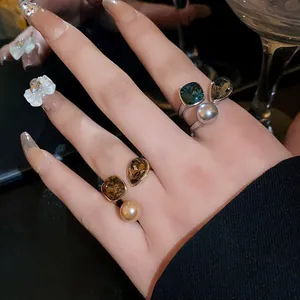 Close-up of vintage gold-plated open rings with colorful square gems and pearls