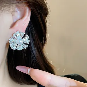 Close-up of 18k gold plated flower earrings with pearl and zircons on ear.
