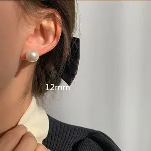 Primer plano detallado de un elegante pendiente de perla blanca de 12 mm en la oreja de modelo