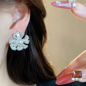 Macro detail of elegant 18k gold plated zircon flower pearl clip-on earring on ear