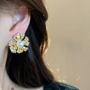 Detailed view of a 18k gold-plated flower earring with pearl and zircon being worn on ear