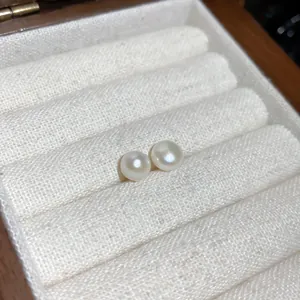 Primer plano de elegantes pendientes de perlas blancas redondas en un joyero de tela