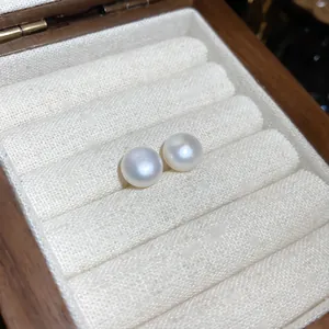Primer plano de elegantes pendientes de perlas blancas en una bandeja de terciopelo