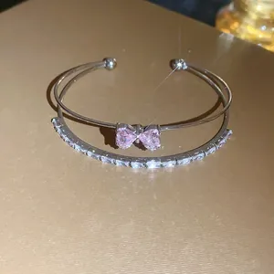 Detailed view of a double-layered silver bracelet featuring a pink zircon bow-knot