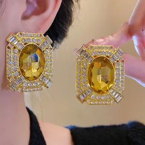 Dettaglio di orecchini vintage con grande cristallo giallo e strass brillanti