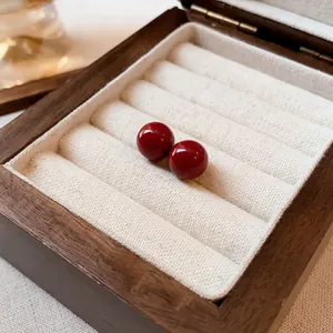 Elegantes pendientes de perlas rojas redondas con agujas de plata en caja de madera