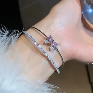 Close-up of pink heart zircon bow bangle and shimmering baguette diamond bracelet.