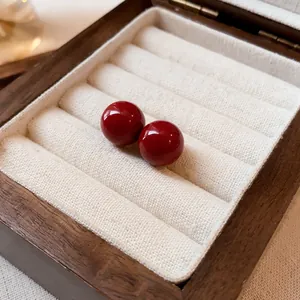 Primer plano de pendientes de bola rojos brillantes en una elegante caja de madera