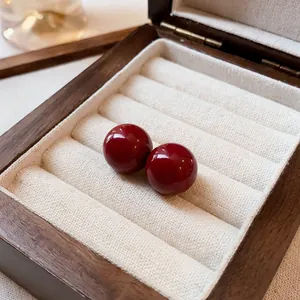 Primer plano de elegantes pendientes de botón redondos de color rojo oscuro en un joyero.