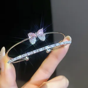 Detail of elegant silver bangle featuring a sparkling pink zircon bow and heart motif.