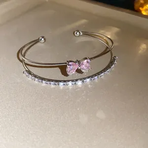 Close-up view of elegant silver double-layer cuff bracelet with pink zircon bow knot.