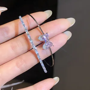 Close-up of heart bow zircon bangle and sparkling silver diamond bracelet for women