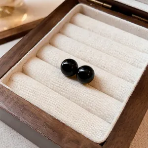 Primer plano de elegantes pendientes de botón redondos de piedra negra en una caja