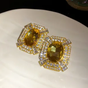 Vista dettagliata di orecchini quadrati vintage con gemme gialle e cristalli brillanti.