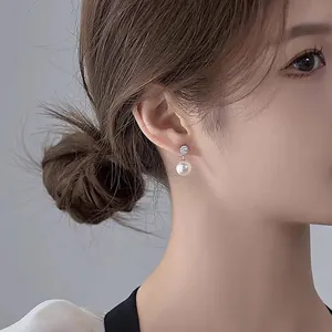 Detail view of elegant silver needle earrings with zirconia and a classic round white pearl.