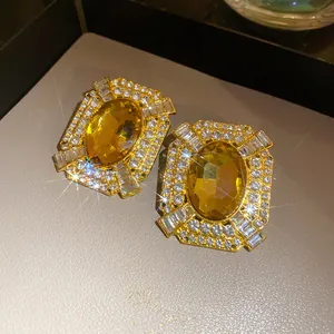 Primo piano di orecchini vintage dorati con pietra gialla e strass scintillanti