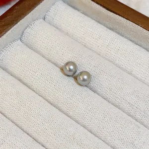 Primer plano de elegantes pendientes de perlas grises en un joyero con textura fina
