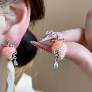 Dettaglio degli orecchini a lobo fragola in resina rosa con goccia in zircone trasparente