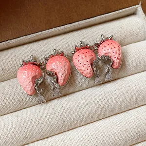 Dettaglio macro di orecchini a lobo a fragola in resina e zirconi