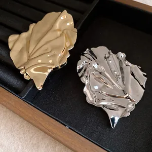 Detailed view of irregular crumpled leaf brooch in gold and silver finish