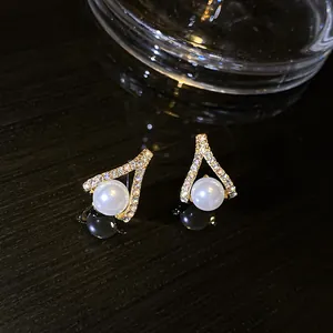 Primo piano di eleganti orecchini a lobo a forma di V con perla e strass
