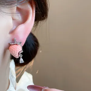 Vista dettagliata di orecchini a perno a fragola in resina rosa con zircone a goccia