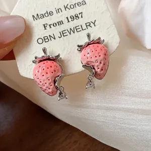 Dettaglio di orecchini a perno a fragola in resina rosa con ago in argento e gocce di zircone.