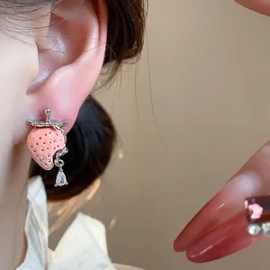 Primo piano di un orecchino a fragola in resina rosa con una goccia di zircone lucente.