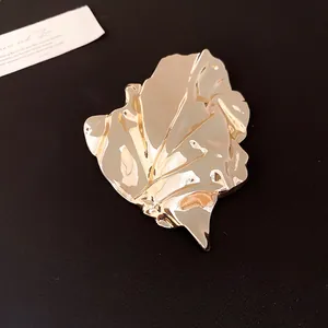 Detailed view of elegant gold metal brooch featuring an irregular wrinkled leaf design