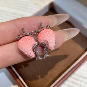 Primo piano dettagliato di orecchini a lobo fragola rosa con gocce di zircone.