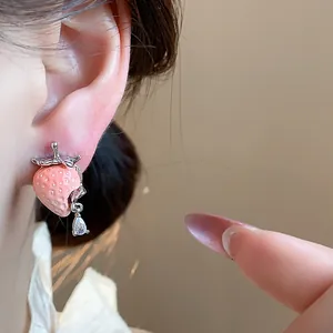 Primo piano di orecchino a fragola in resina rosa con una goccia di zircone scintillante.