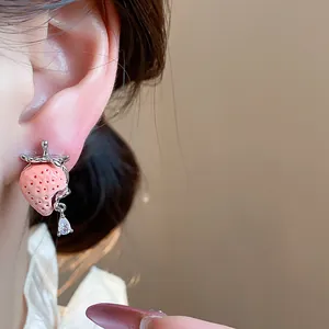 Primo piano di un orecchino a fragola in resina con goccia di zircone all'orecchio.
