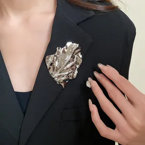 Large silver irregular crumpled leaf brooch on black blazer for elegant styling