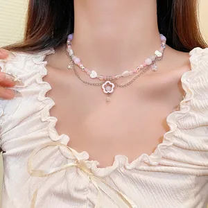 Close-up of a Y2K style beaded necklace with a pink flower pendant on a model's neck.