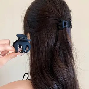 Detailed view of a matte black wavy hair claw clip worn in a half-up hairstyle by a model