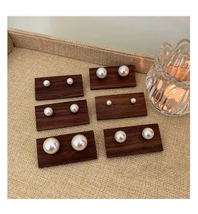 Detailed view of high-luster pearl stud earrings in six different sizes on wood.