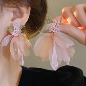 Dettaglio di orecchini a fiore in rete rosa dallo stile floreale forestale raffinato