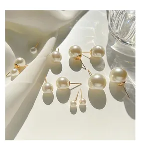 Close-up of silver needle pearl stud earrings in various sizes with high-gloss finish.