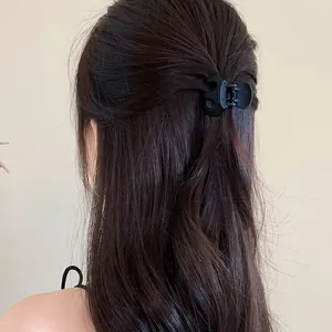Rear view showing a black matte wavy hair claw clip holding long hair in a half-up style