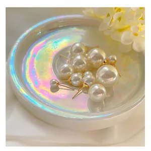 Close-up of high-luster pearl stud earrings in various sizes on an iridescent dish