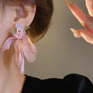 Dettaglio orecchino a fiore stile foresta con nastro in mesh rosa e perline