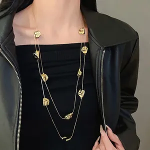 Élégant collier long double épaisseur en or avec breloques métalliques froissées